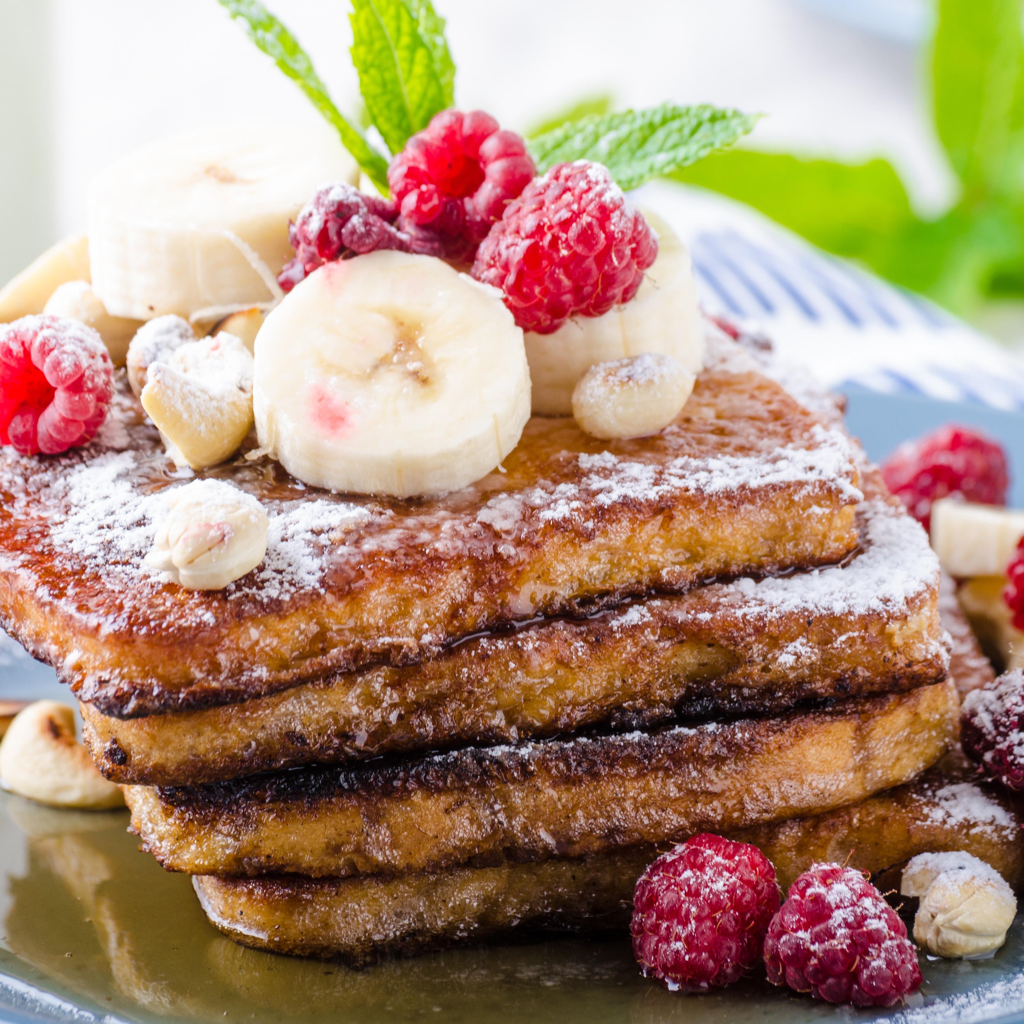 Classic french toast topped with syrup, banana, raspberries and powdered sugar.