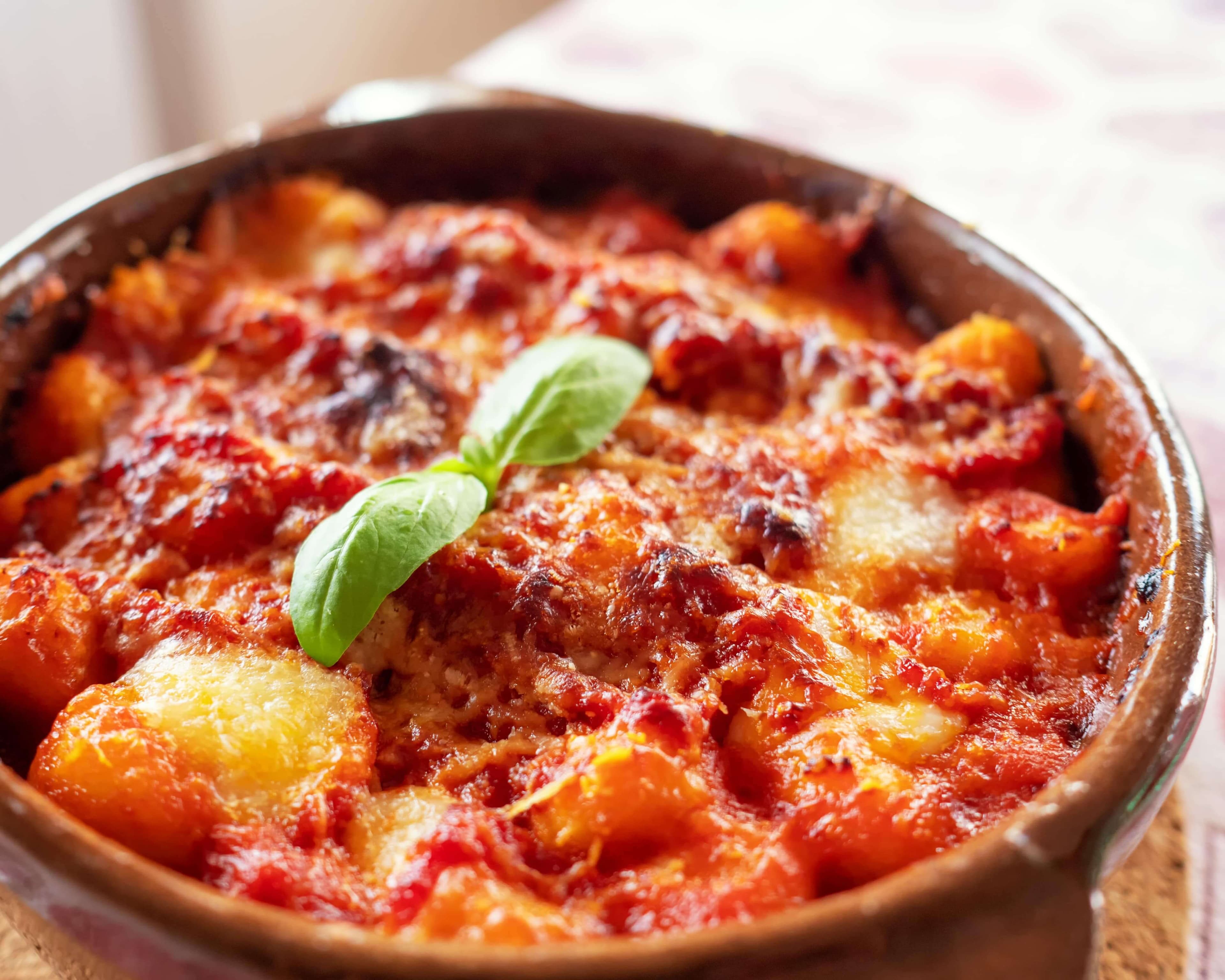 Rich tomato chorizo gnocchi bake topped with a basil leaf