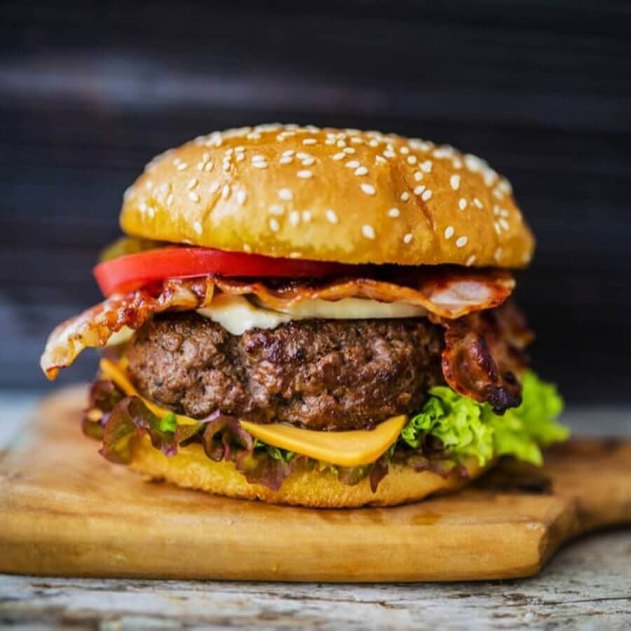 Perfect homemade beef burger placed into a brioche bun with added bacon, lettuce, tomato and melted cheese. 